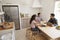 Three teens study in kitchen using computers, elevated view