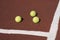 Three tennis balls on brown synthetic court