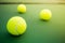 Three tennis balls on green hard court