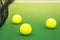Three tennis balls on green hard court