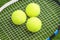 Three tennis balls lie on a tennis racket strings. over green la