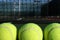 Three Tennis balls with the net in background