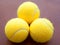 Three tennis balls together in yellow