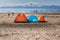 Three tents situated on a beach, on a sunny day