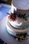 Three-tier cake, white with blue spots, decorated with flowers, on a blue background