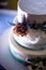 Three-tier cake, white with blue spots, decorated with flowers, on a blue background