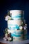 Three-tier cake, white with blue spots, decorated with flowers, on a blue background