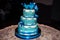 Three-tier wedding cake with blue mastic and blue hearts at the wedding celebration, for the newlyweds