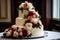 a three tiered wedding cake with flowers on top of a white table clothed tablecloth with a window in the background and a window