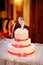 Three-tiered white wedding cake with red ribbons