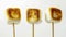 Three Toasted Marshmallows On Sticks Against A White Background
