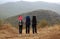 Three tourists with backpacks stand on a mountain slope.