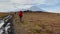 Three tourists with large backpacks are walking along the tundra. Trekking in the Klyucheskiy park of volcanoes.