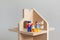 Three toy figures of men-a man, a woman and a child in a wooden toy house. A symbol of a family in their own new home.