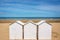 Three traditional white wooden beach huts on the beach of Villers, Normandy France