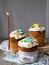 Three traditionally baked orthodox easter cakes with glace icing and bright blue and yellow flowers on wooden background with lace