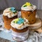 Three traditionally baked orthodox easter cakes with glace icing and bright blue and yellow flowers on woooden