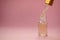 Three transparent bottle with cosmetic serum and pipette closeup on a pink background. Place for text