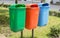 Three trash bin in different colors on a park