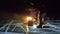 Three travelers by fire right on ice at night. Campground on ice. Tent stands next to fire. Lake Baikal. Nearby there is