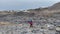 Three travelers with large backpacks are walking along the stone fields of Kamchatka.