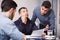 Three troubled men discussing documents at desk