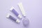 Three tubes with cosmetic creams, one jar with cosmetics on a lilac background