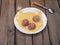 Three turkey meatballs for frying on a plate with corn grits on a wooden plank table