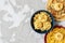 Three types of pasta on ceramic plates of different colors on a textured gray background