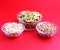Three types of snacks in glass bowl: pumpkin seeds, peanuts and Pistachio nuts with red background