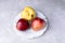 Three ugly apples on white  figured plate on grey concrete background.