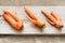 Three ugly carrots are lying on grey wooden planks on burlap.