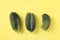 Three ugly cucumbers on bright yellow background. Concept Organic Food, View from above