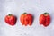 Three ugly strawberries on grey concrete background.