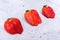 Three ugly strawberries are lying diagonally on grey concrete background.