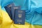 Three Ukrainian biometrical passports on folded waving flag of Ukraine country