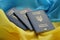 Three Ukrainian biometrical passports on folded waving flag of Ukraine country