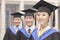 Three university graduates wearing graduation gowns and mortarboards smiling in a row