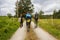 Three unknown pilgrims walking on Camino de Santiago. Group of tourists with backpacks on village road. Active people on the way.