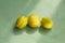 Three unripe yellow-green apricots in the morning sun on a textured green background. Latest trend - Eating unripe fruits