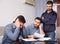 Three upset males with papers at table