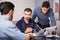 Three upset males with papers at table