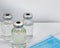 Three Vaccine vials against virus with medical mask