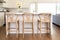 three varnished oak counter chairs in a neutral-toned kitchen