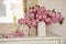 Three vases with sakura twigs in beige vases in the home interior. Mirror at the window in the dressing room