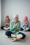 Three veiled women sit on the floor praying