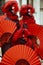 Three Venice masks dressed in red and black costumes holding red fans at the Venice Carnival in Venice Italy