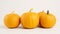 Three vibrant pumpkins on a white backdrop, simple and clean