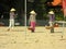 Three Vietnamese women in conical headdresses walk along the beach