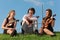 Three violinists sit on grass against sky